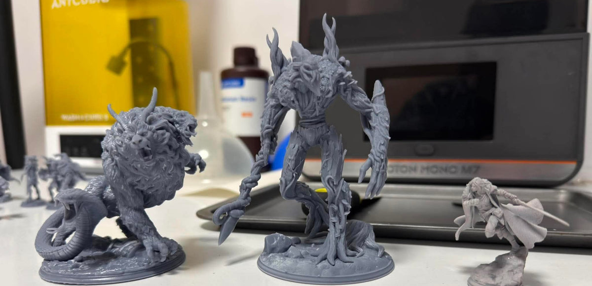 Unpainted resin miniatures next to a resin 3D printer in the workshop