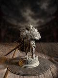 Knight miniature in heavily feathered owl-motif armor, standing over scattered scrolls and rubble, greatsword strapped to the back