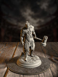 Bearded barbarian miniature mid-swing with a massive totem-carved warhammer, tribal tattoos visible on bare arms